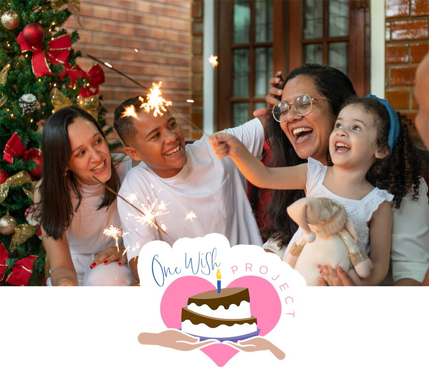 A family embraces and plays with sparklers with the One Wish Project logo embedded in the foreground